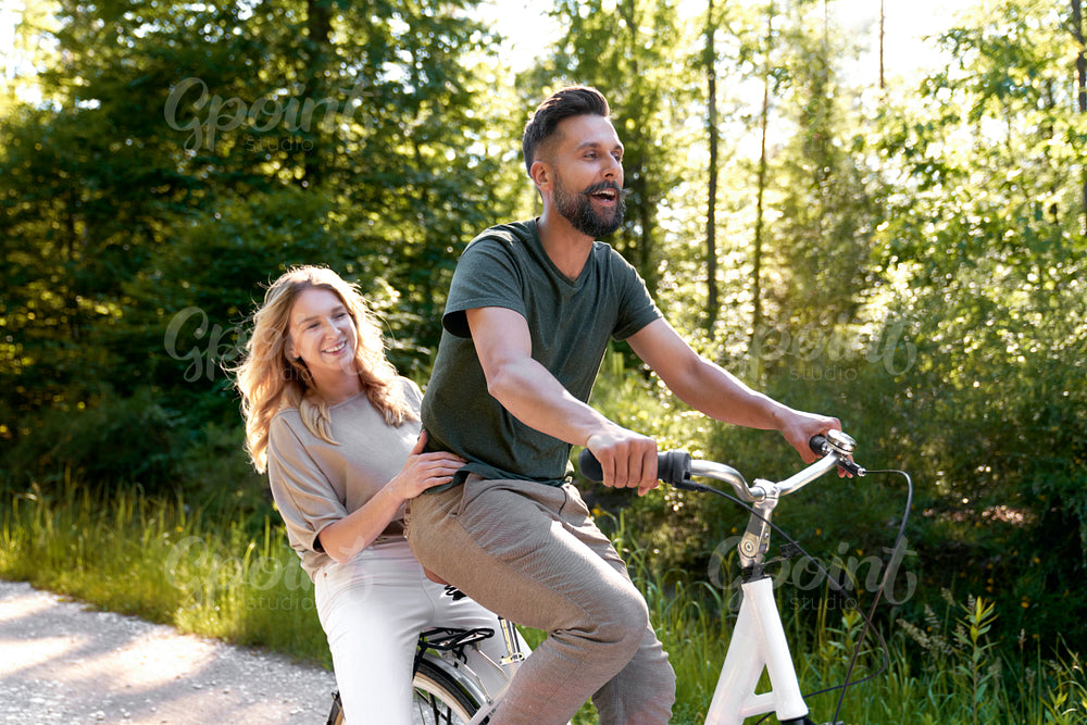 Playful couple having fun on a bike in the woods