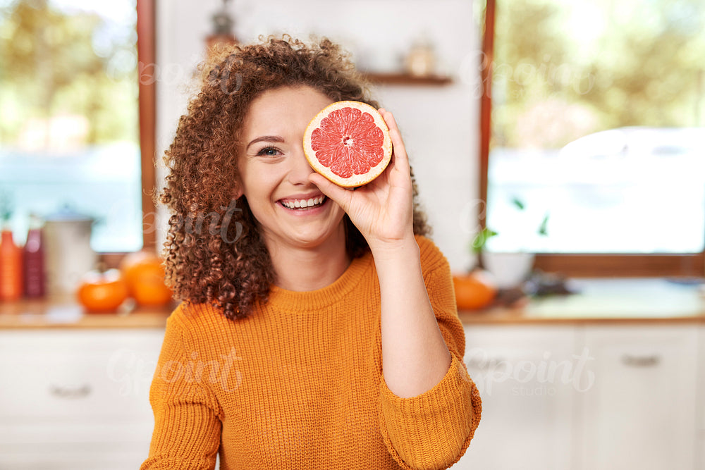 Portrait of  beautiful woman having fun with fruit in kitchen