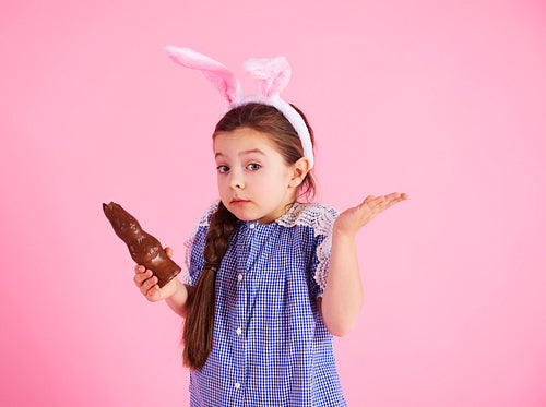 Confused girl eating chocolate rabbit in studio shot