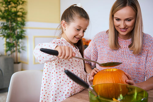 Mother helping daughter in carving pumpkins