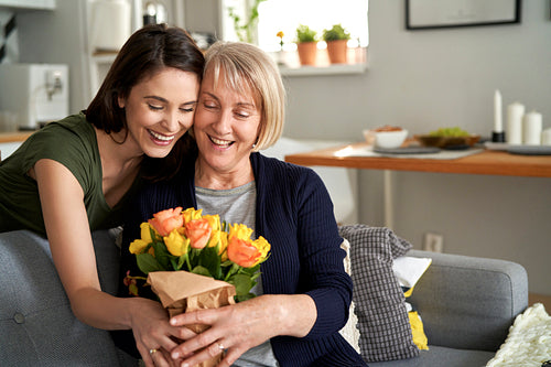 Happy daughter giving flowers to her mother