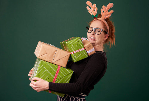 Funny woman carrying stack of christmas gifts
