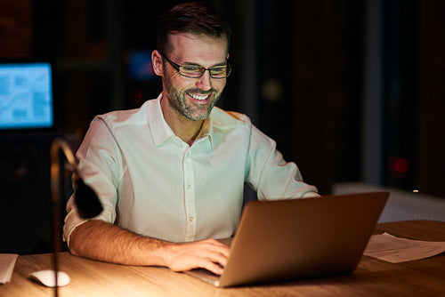 Smiling man using a laptop at night