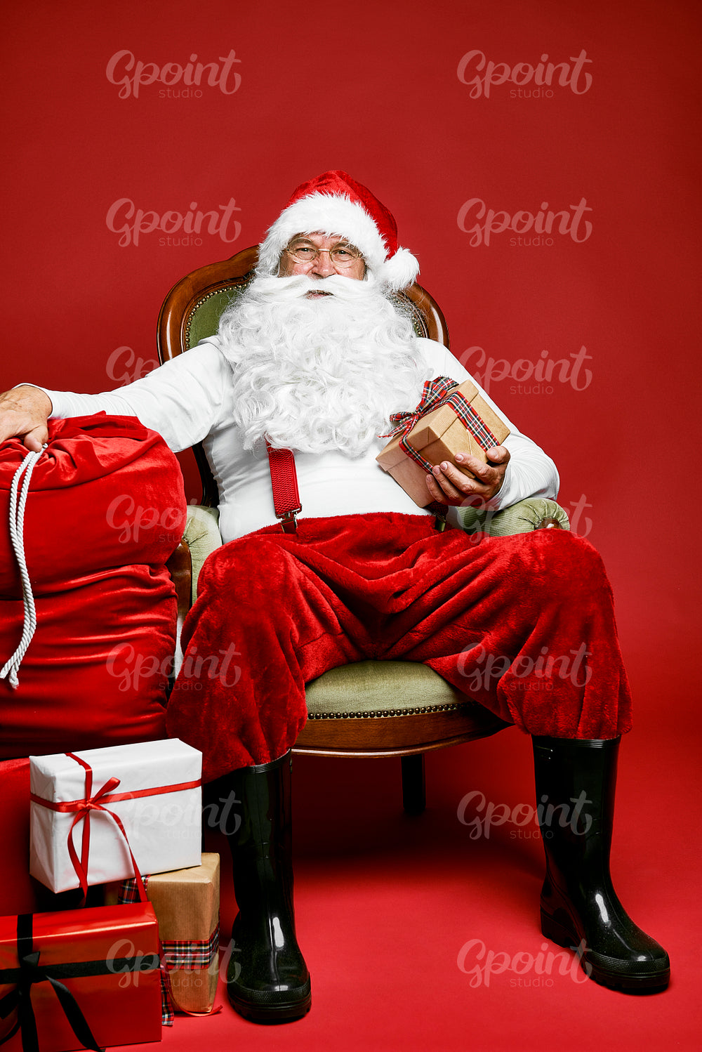 Caucasian Santa Claus sitting on the retro chair with Christmas presents