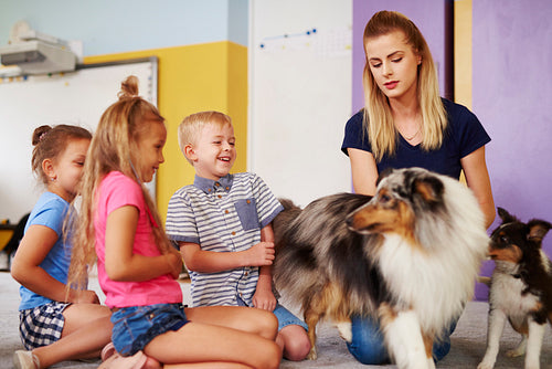 Group of children having fun with dog during therapy