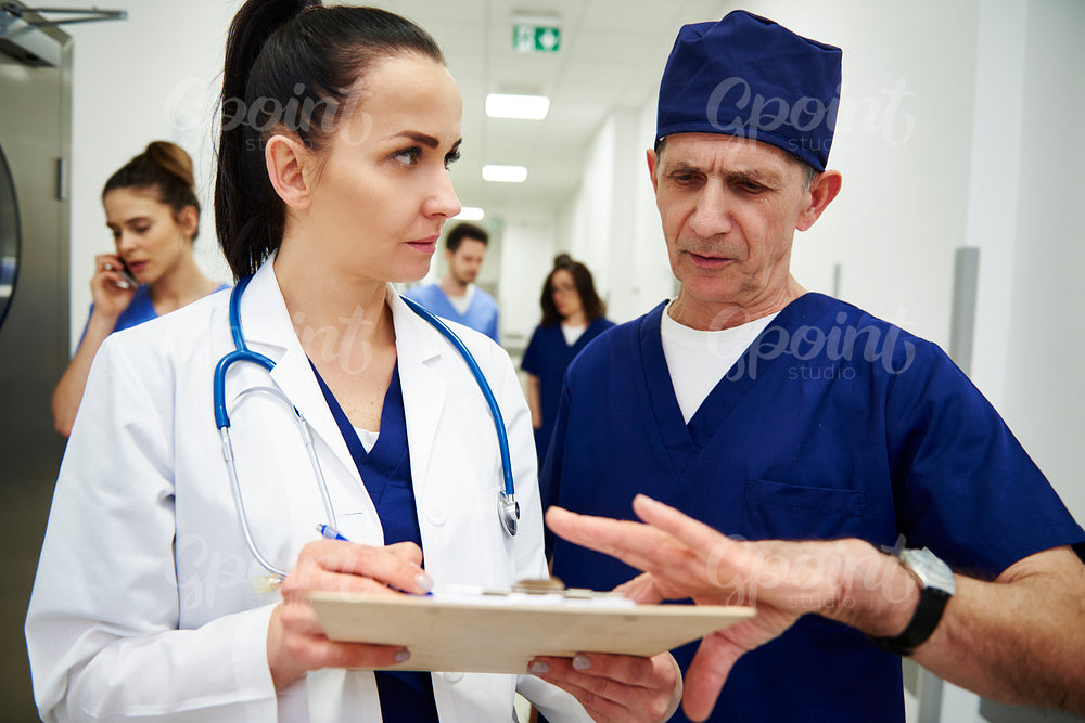 Two doctors discussing medical records in the corridor