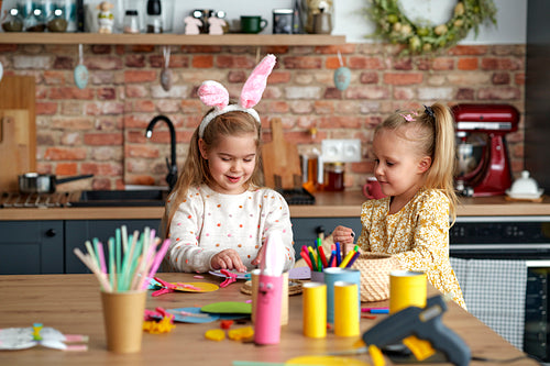 Two little girls preparing decorations for Easter at home