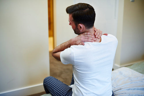 Rear view of man suffering from neck pain