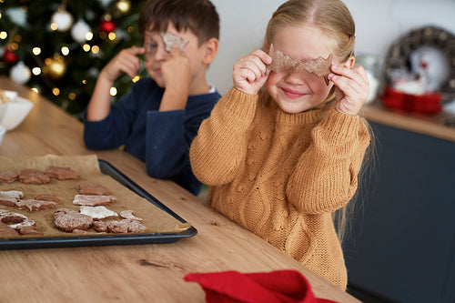 Girl covering eyes with homemade gingerbread cookies