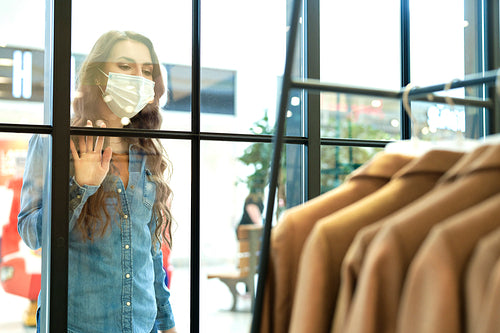 Woman in protective mask admiring window display in shopping mall