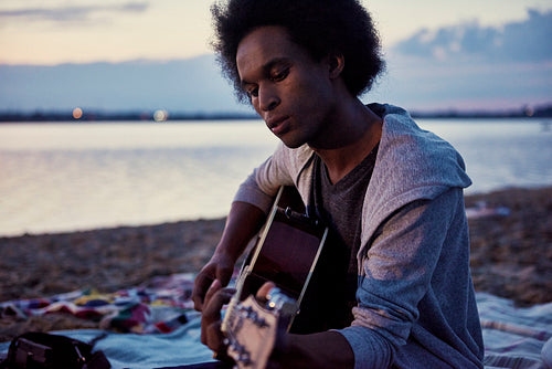 African man playing the guitar on the beach at night