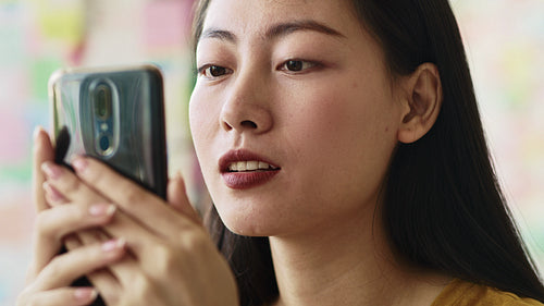 Handheld view of focused young woman looking at mobile phone