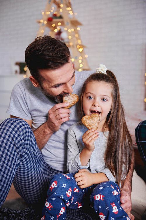 Father and daughter eating gingerbread at christmas