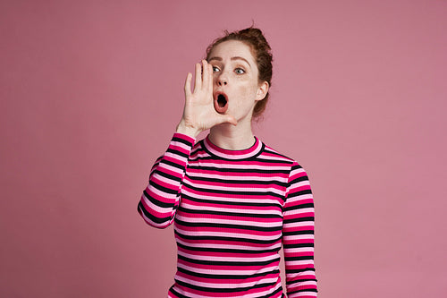 Studio shot of young woman screaming and standing on the pink background