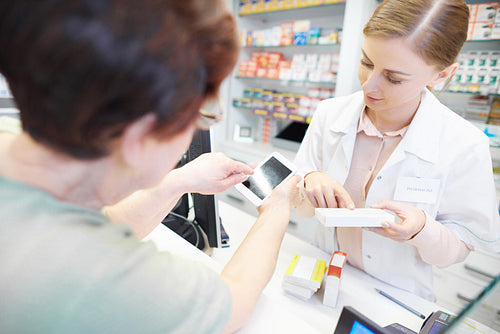 Customer using cell phone at pharmacy checkout