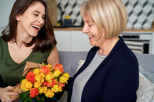 Happy woman giving mom bouquet of flowers