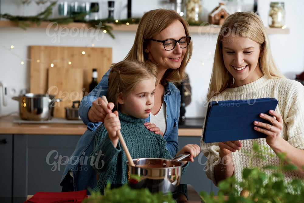 Three generations of women looking for recipe on the tablet