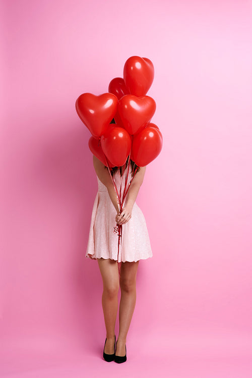 Woman holding bunch of heart shape balloons