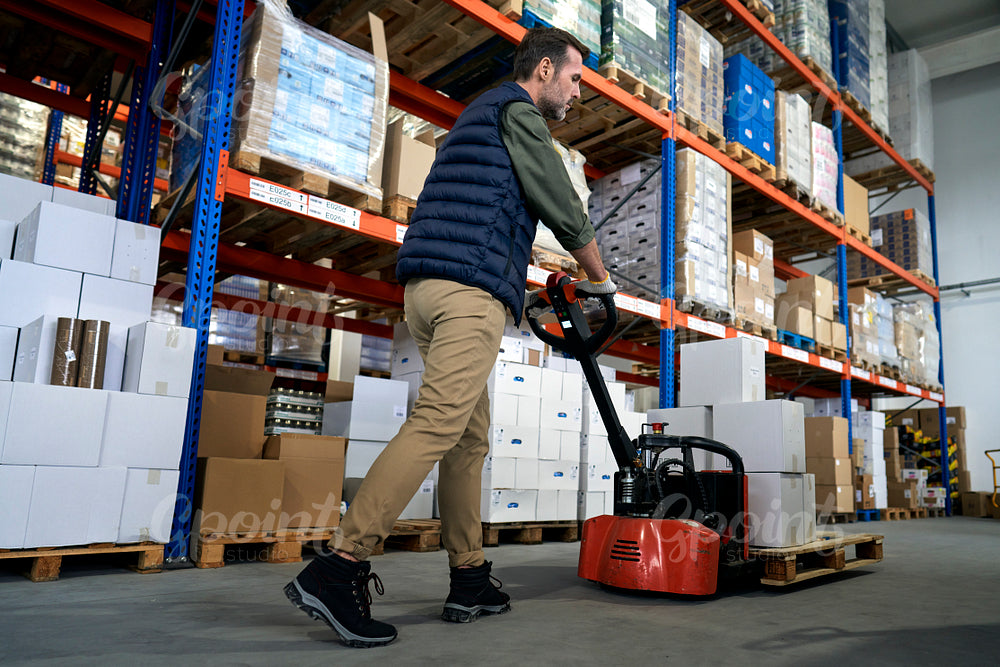 Adult caucasian working in warehouse and using push cart 