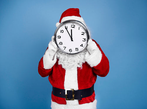 Santa Claus holding clock in front of his face
