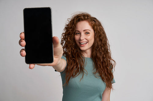 Redhead showing screen of mobile phone