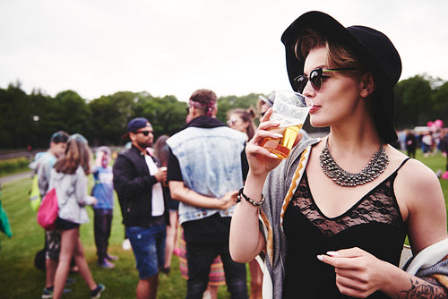 Fashionable woman drinking a beer at festival