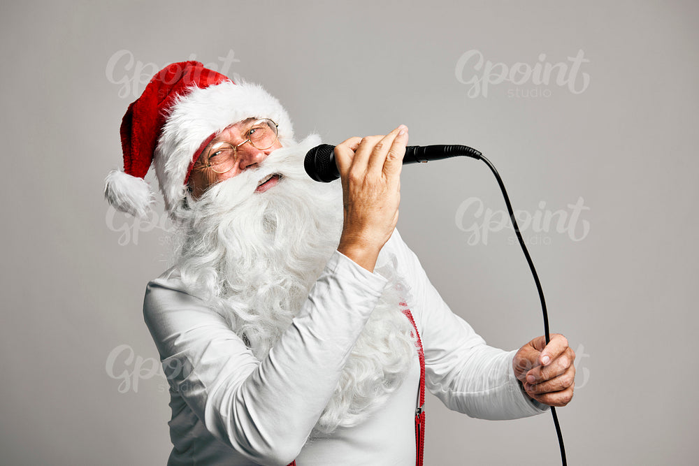 Caucasian Santa Claus on grey background singing Christmas songs