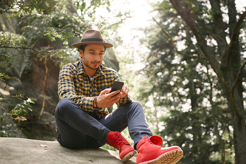 Man using mobile phone and sitting on rock