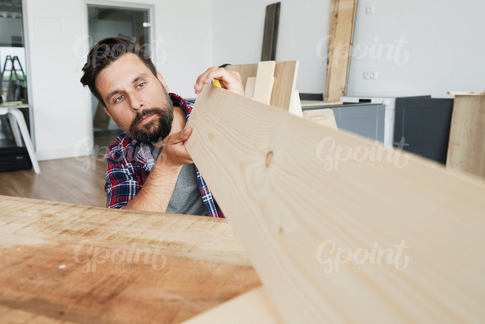 Carpenter looking at a wooden plank
