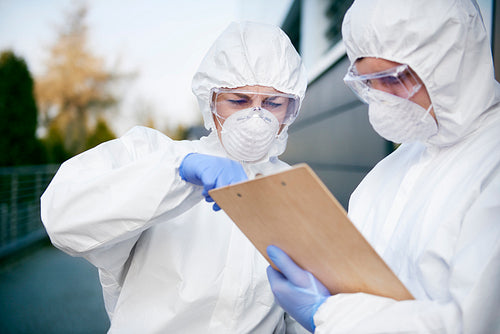 Two technicians with document wearing a protective suit