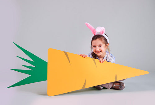 Smiling girl holding a big carrot with copy space