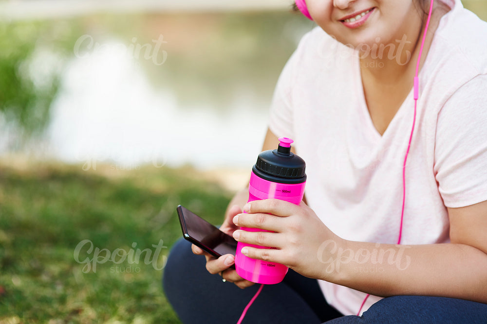 Athlete's hands holding sports drink and mobile phone