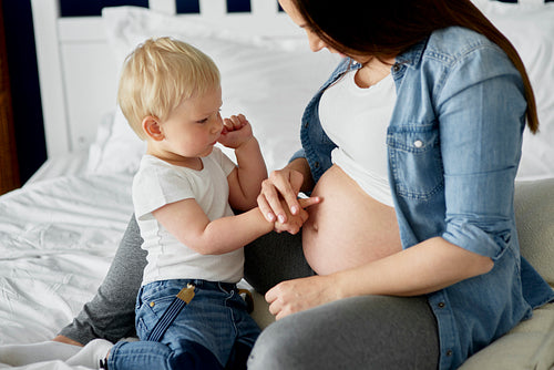 Little boy touching abdomen of his pregnant mother