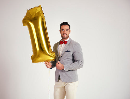 Young man with golden balloon celebrating first birthday his company