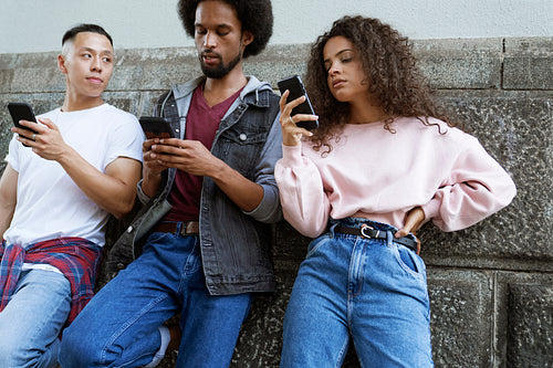 Bottom view of three young people standing with mobile phones
