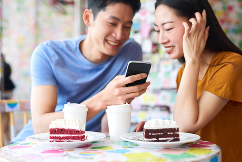 Excited couple with mobile phone in a cafe