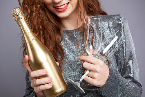 Young woman holding champagne flute and bottle