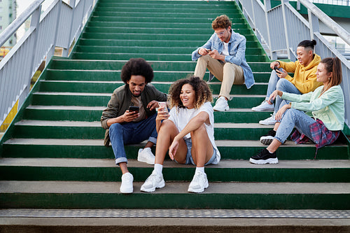 Group of young people sitting on stairs with mobile phones