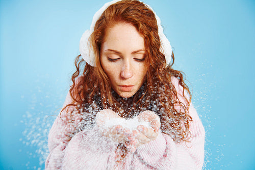 Young woman blowing fake snow at studio shot