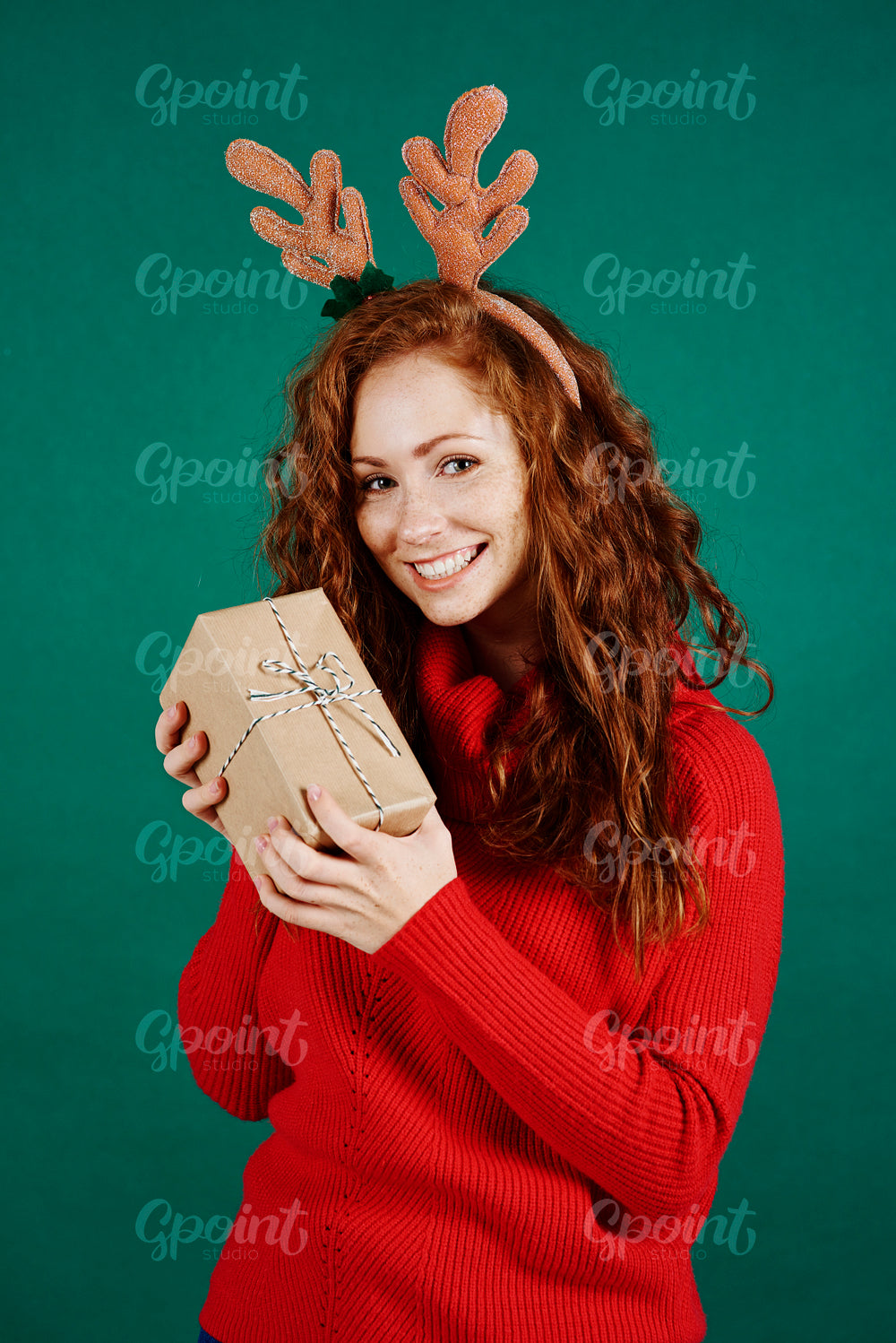 Portrait of happy girl holding christmas present at studio shot