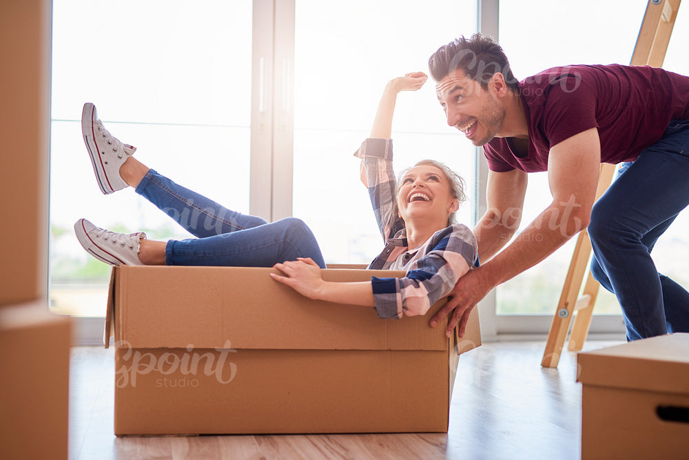 Happy couple having fun with boxes during move house