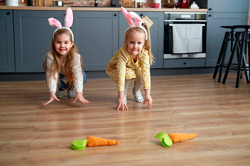 Two little girls playing handmade carrots on the floor