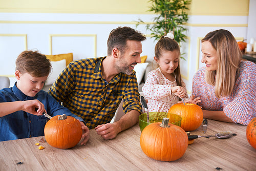 Children carving pumpkins with parents