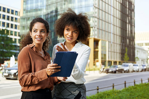 Two businesswomen with digital tablet outdoors