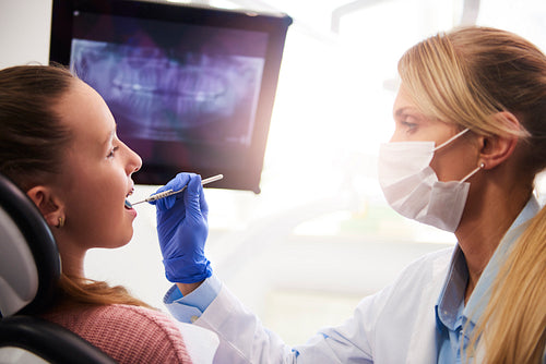Female orthodontist using dental mirror during checkup
