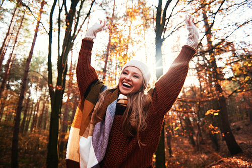 Happy beautiful woman with hands up in autumnal forest