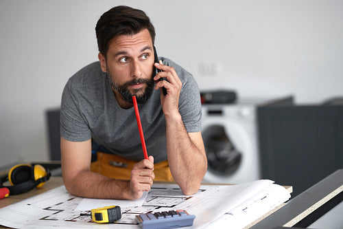 Front view of man with blueprints talking on the phone