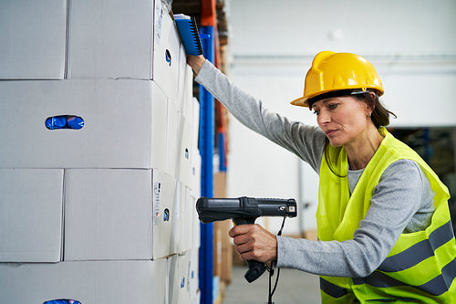 Adult caucasian woman using bar code reader in a warehouse