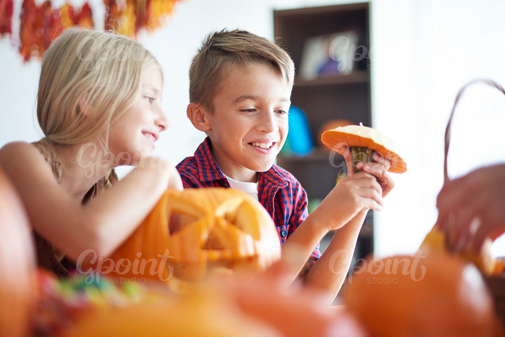 Cute siblings with Halloween pumpkins at home