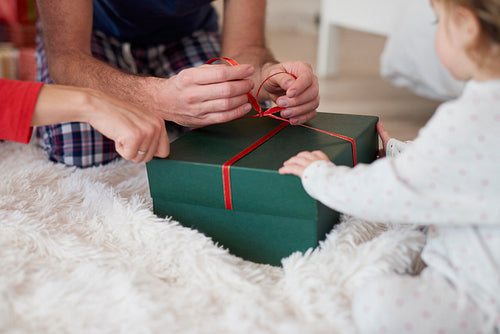 Close up of baby opening Christmas present with parents
